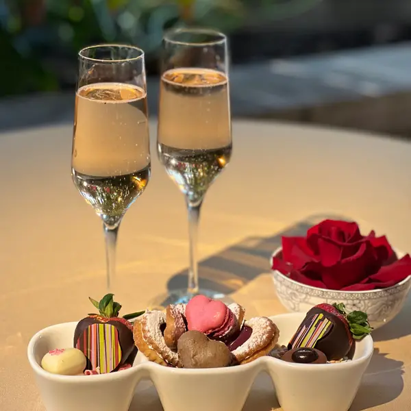A table with a plate of desserts and two glasses of sparkling wine.