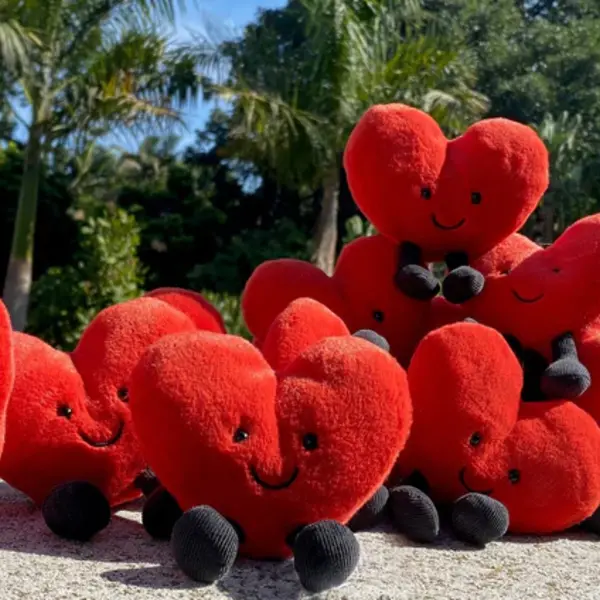 A group of red heart-shaped plushies in a garden.