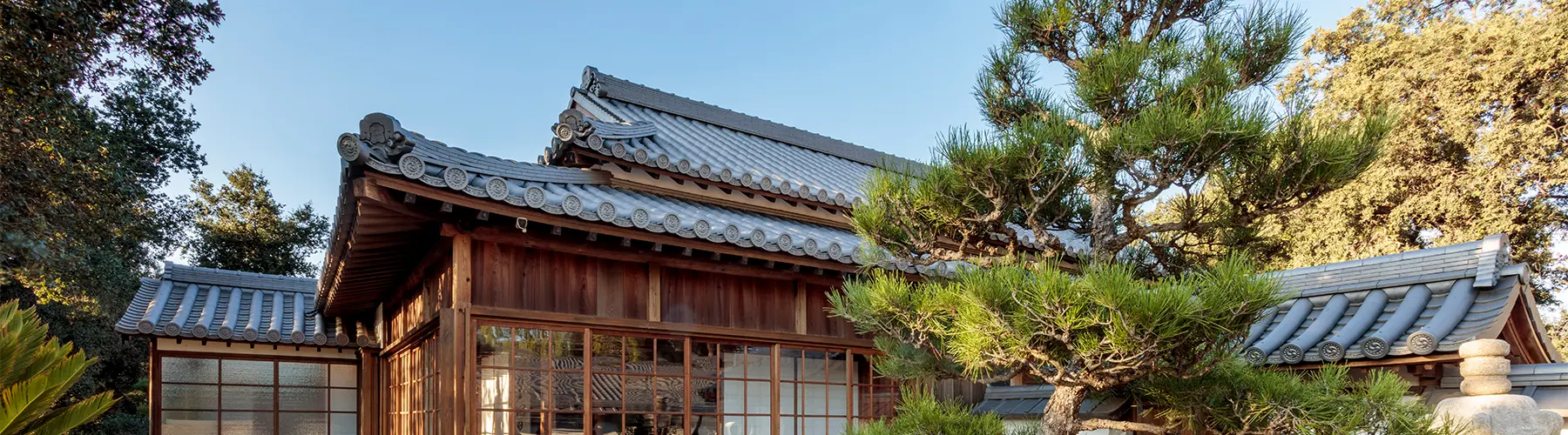 A traditional Japanese house in a garden with trees.