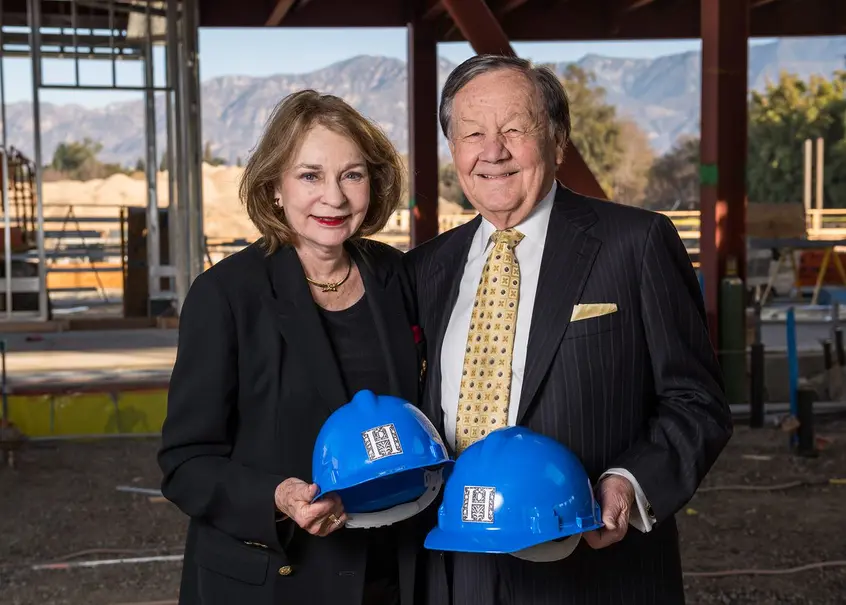 couple at construction site holding safety hats
