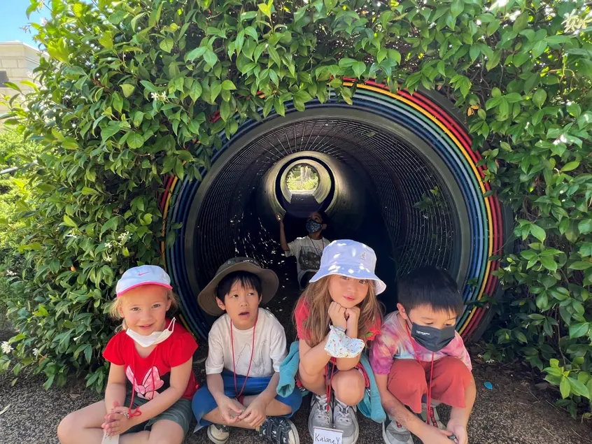 young kids sitting by garden rainbow tunnel