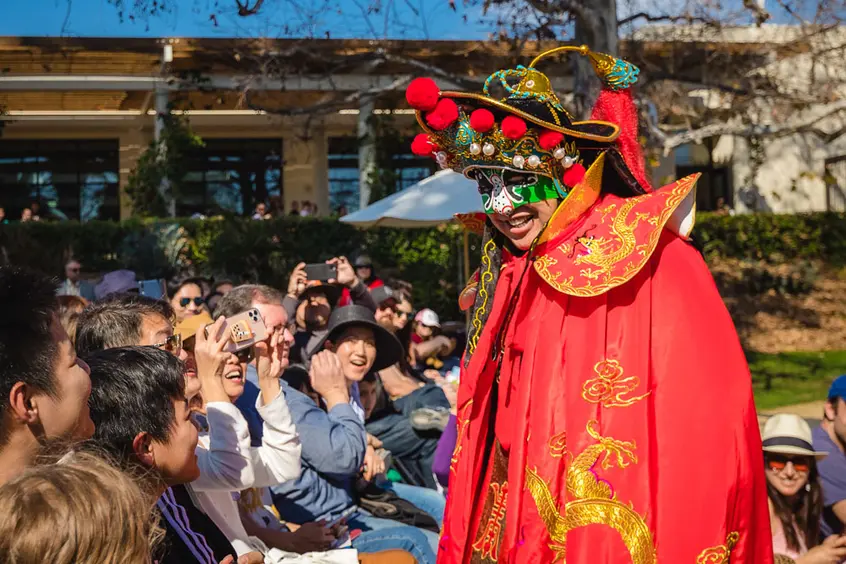 A masked performer interacts with an audience.