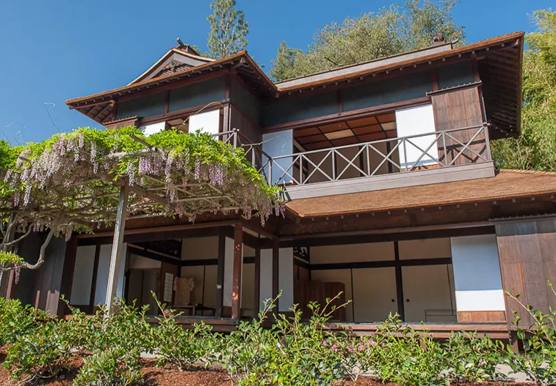 A large, two story Japanese-style house with sliding walls open onto a garden.