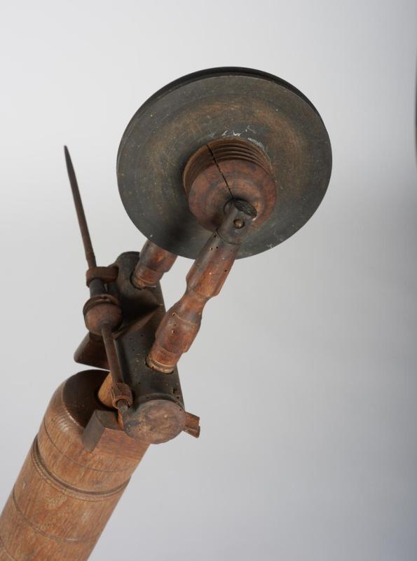 Close-up view of the bobbin of a wooden spinning wheel; as yarn is spun it is wrapped around the bobbin.