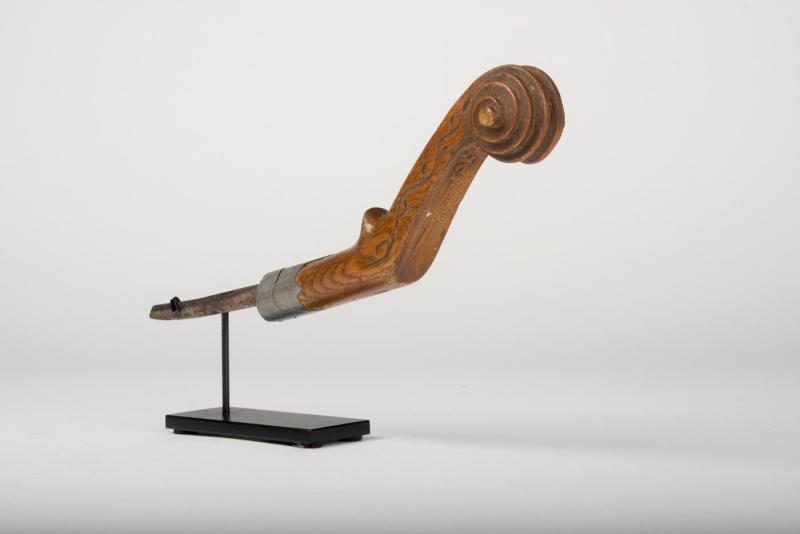 Crooked knife with metal blade attached to wooden handle with spiral relief and carved vine motif at the handle top.