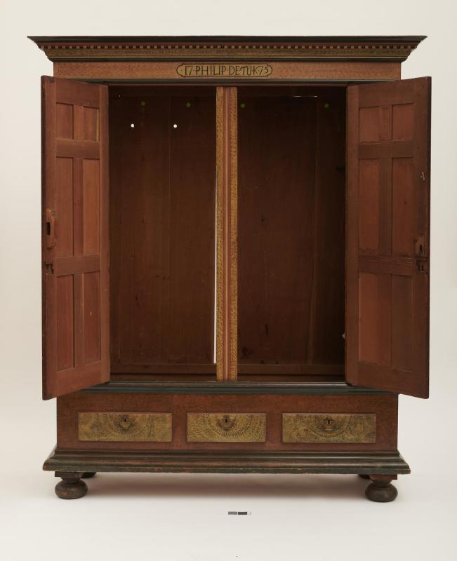 Frontal view of large wooden wardrobe with panels opened to reveal interior; three drawers across bottom and cornice at top. 