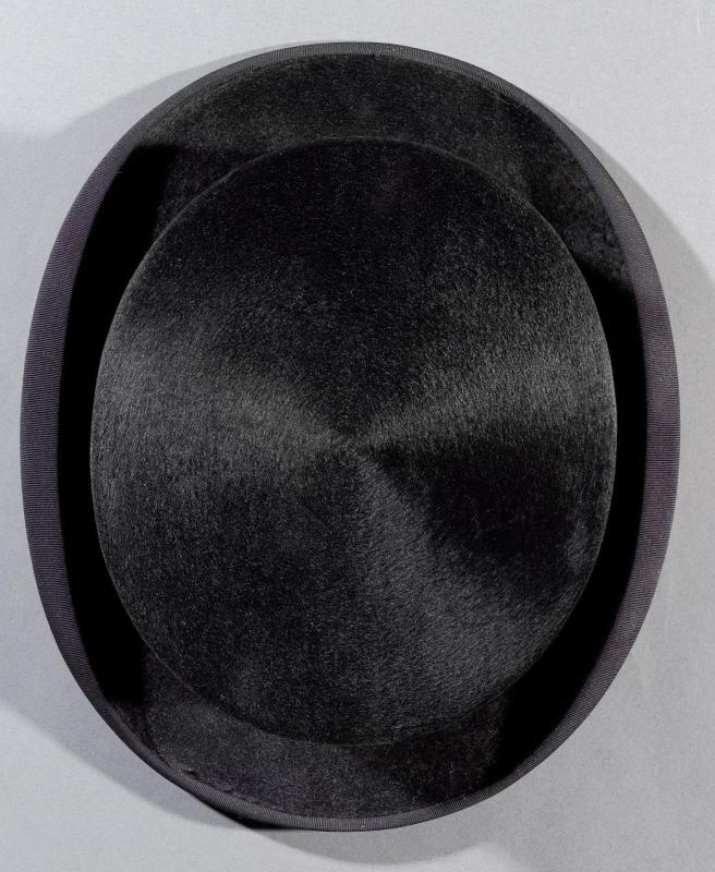 Overhead view of top of black beaver-skin top hat sitting on plain surface.