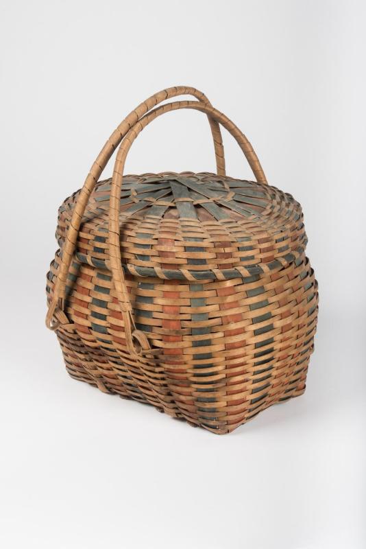 Oval-shaped woven basket with lid and movable handles, with indigo and red splints interwoven throughout.