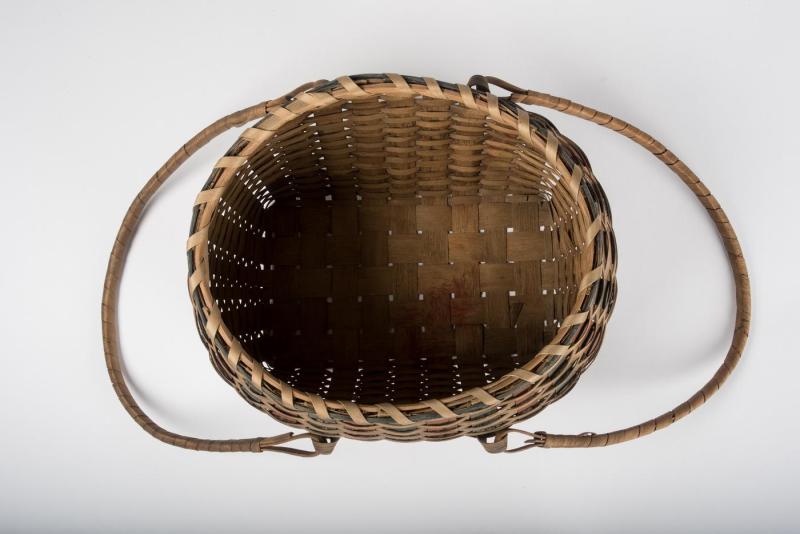 Overhead view into the interior of an oval-shaped woven basket with indigo and red splints interwoven throughout.