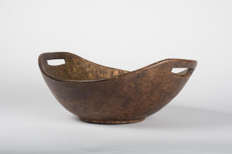 Bowl made from dappled burl wood with curved, U-shaped rim and cutout handles.