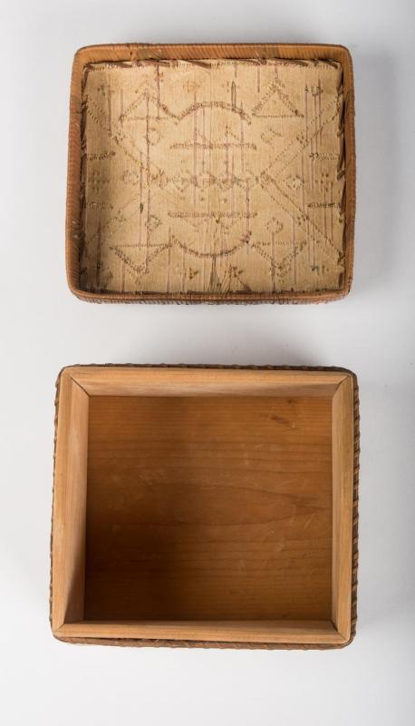 Plain wood interior of a square box with top and lid arranged separately. 