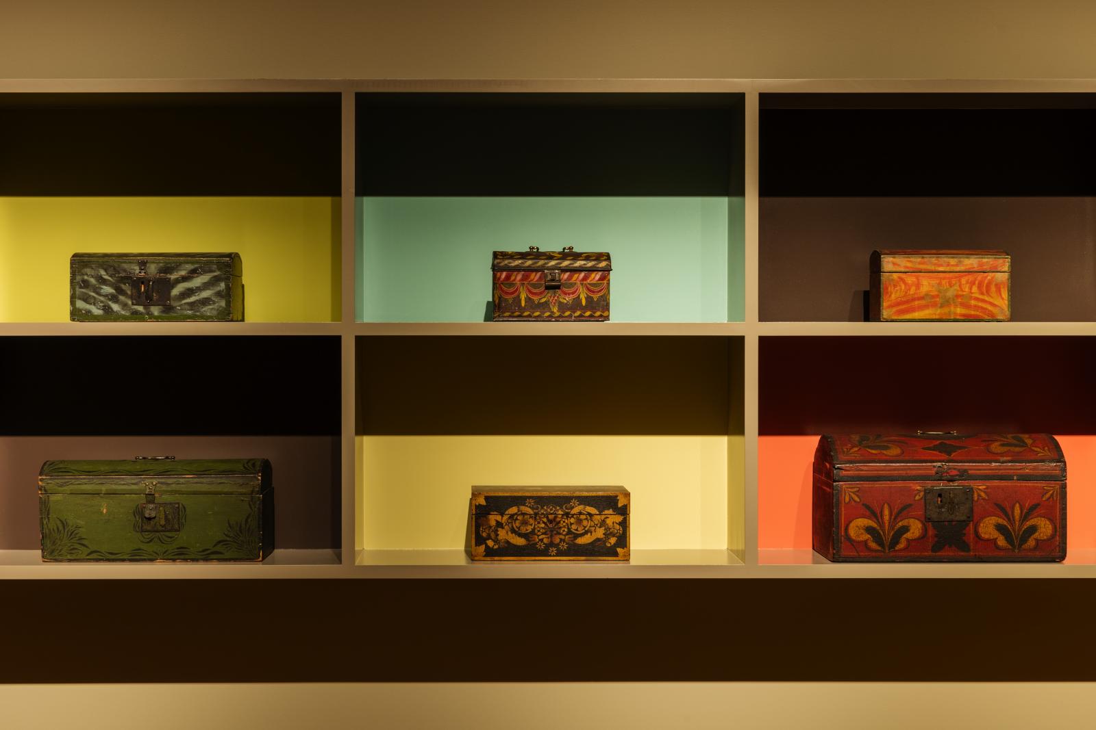 Six boxes displayed in a shelf with different color backgrounds behind each box.