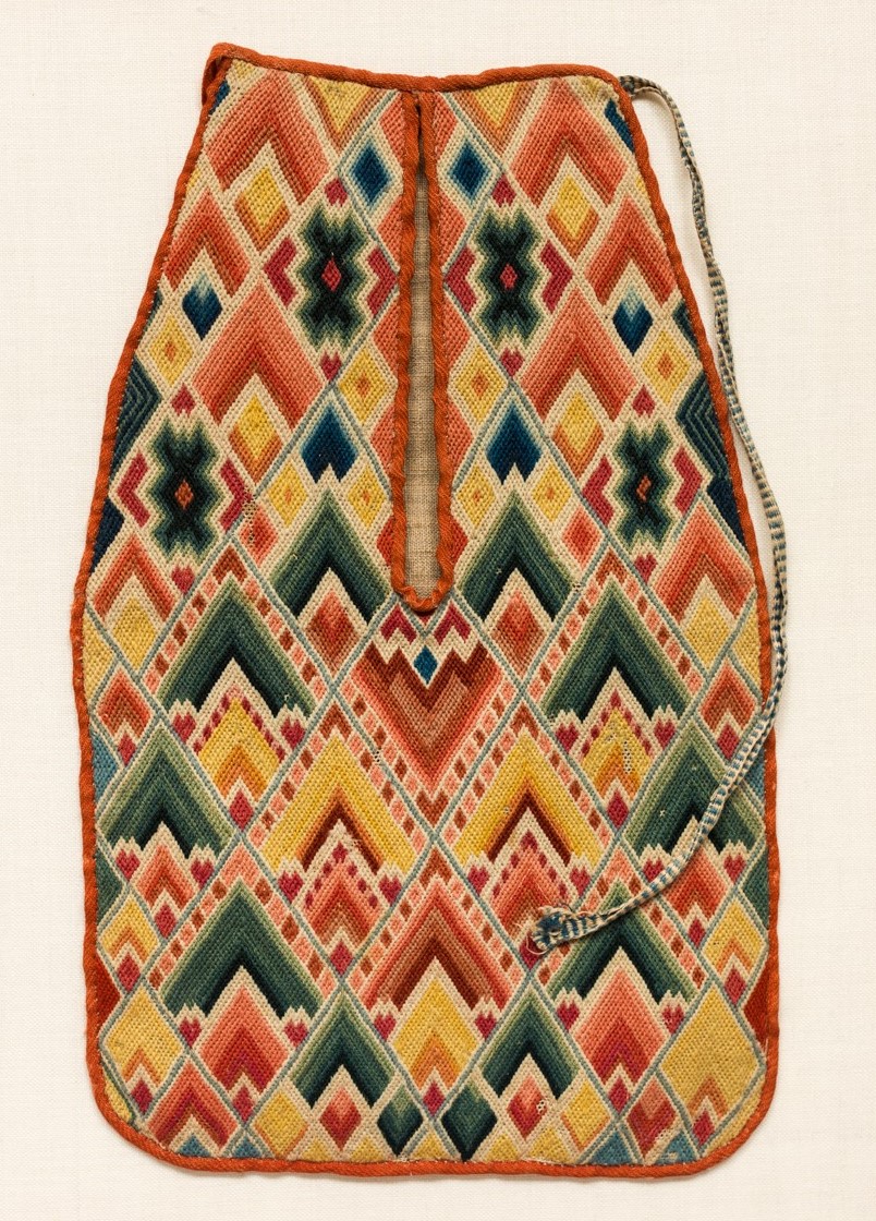 Right pocket belonging to pair of embroidered fabric pockets in the shape of small sacks with multicolored flame-like patterns stitched neatly in combinations of red, green, blue and yellow.