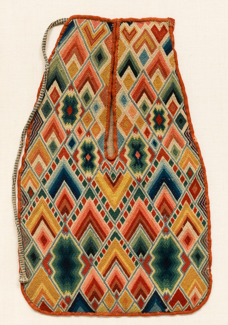 Left pocket belonging to pair of embroidered fabric pockets in the shape of small sacks with multicolored flame-like patterns stitched neatly in combinations of red, green, blue and yellow.