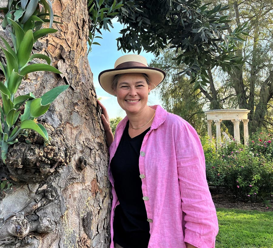Nicole Cavender stands next to a tree in the Huntington Rose Garden.