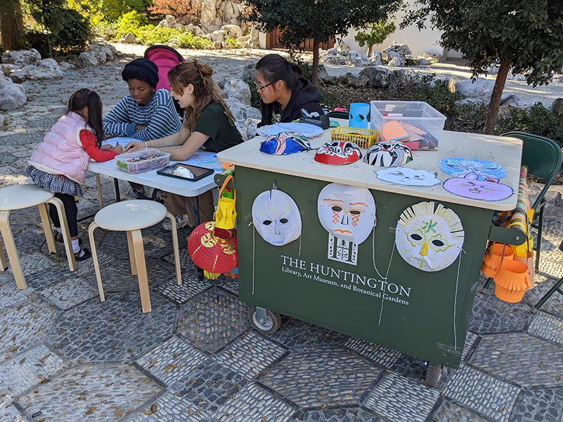 Volunteers helping a child draw a mask.