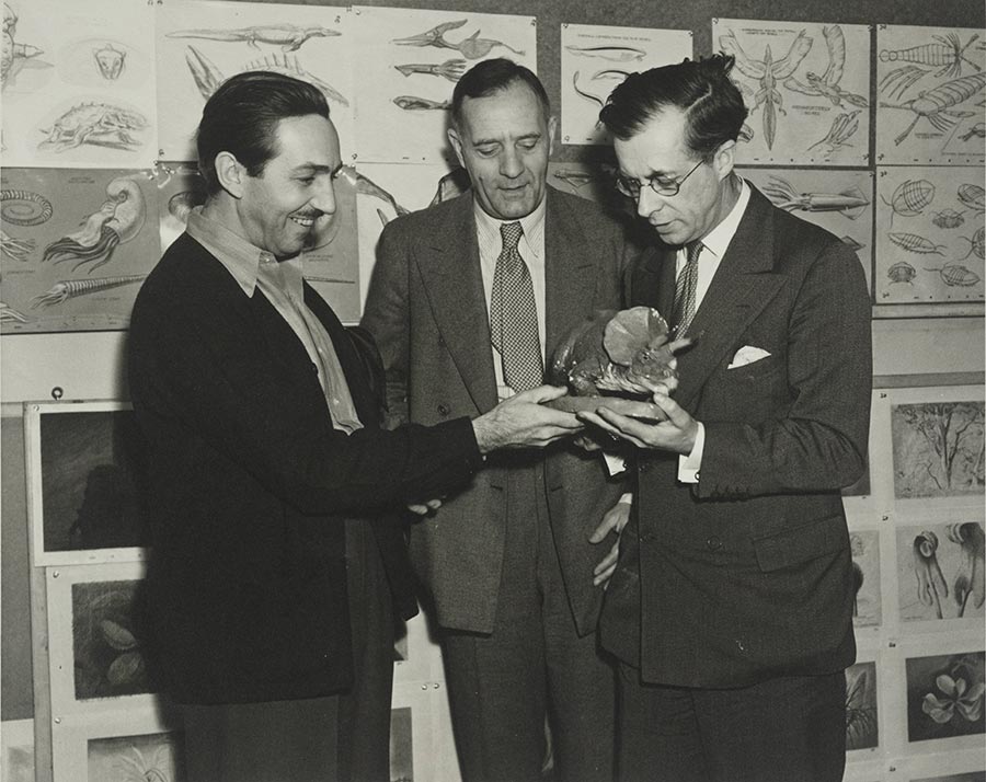 Walt Disney, Edwin Powell Hubble, and Sir Julian Huxley looking at a dinosaur model.