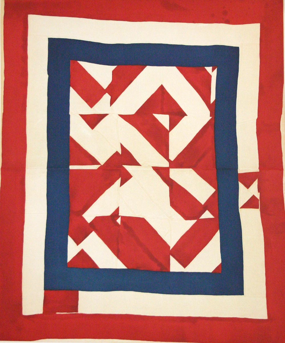 A geometric quilt made from red, cream, and blue shapes.