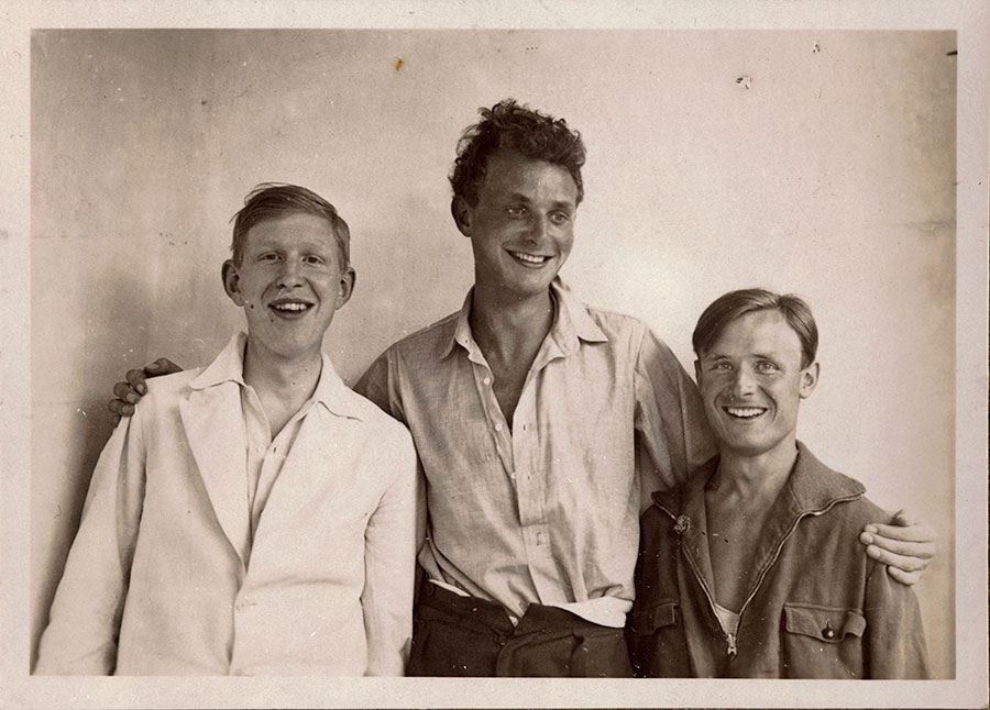 Black-and-white photo of three young men smiling.