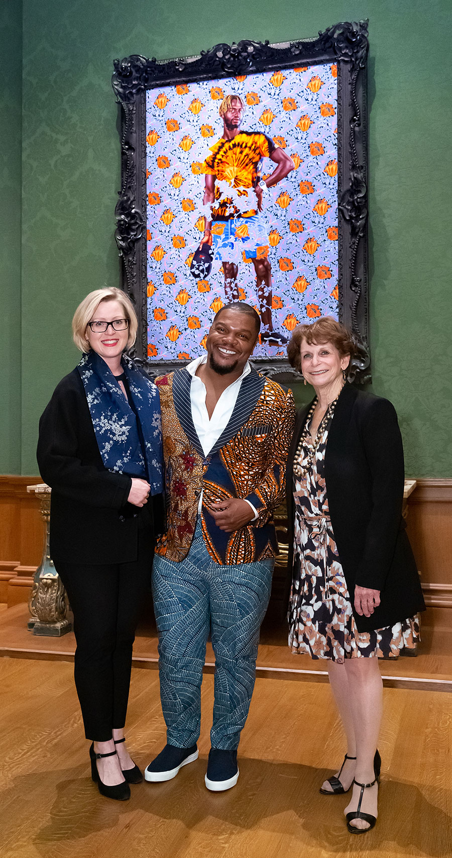 Three people inside an art gallery with the Kehinde Wiley painting A Portrait of a Young Gentleman.