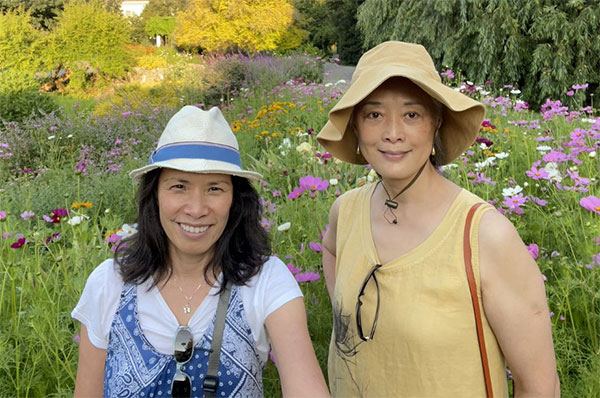 Two friends stand near a field of flowers.