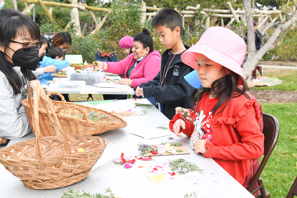 A group of children participate in activities at a table in a garden.