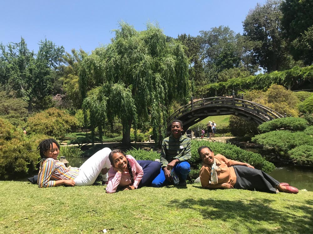 A family rests in the grass on a sunny day in a Japanese style garden.