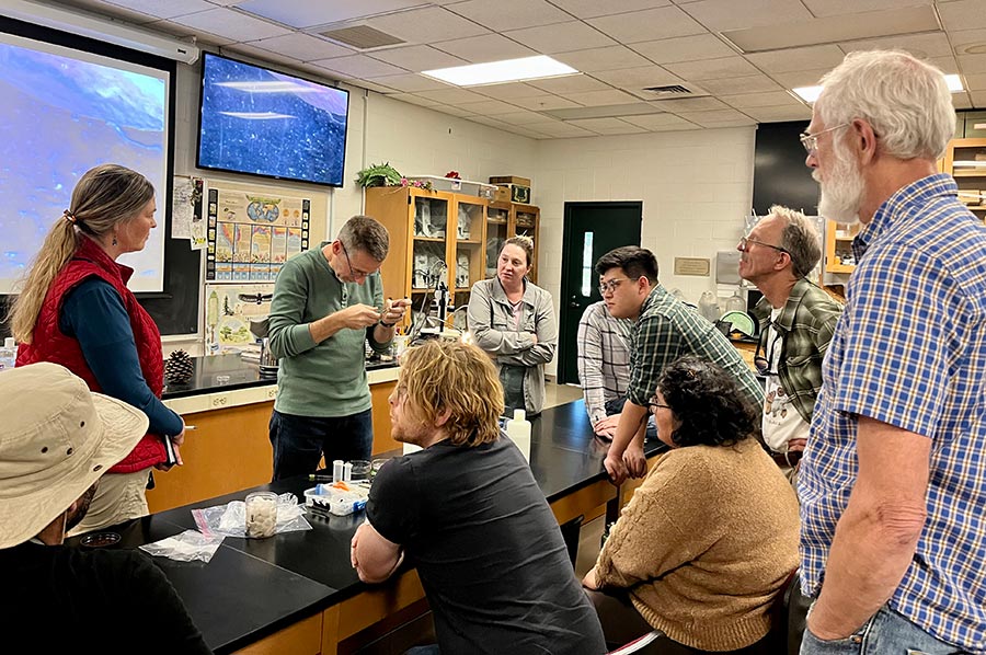 People in a classroom observe a demonstration of mollusk identification.