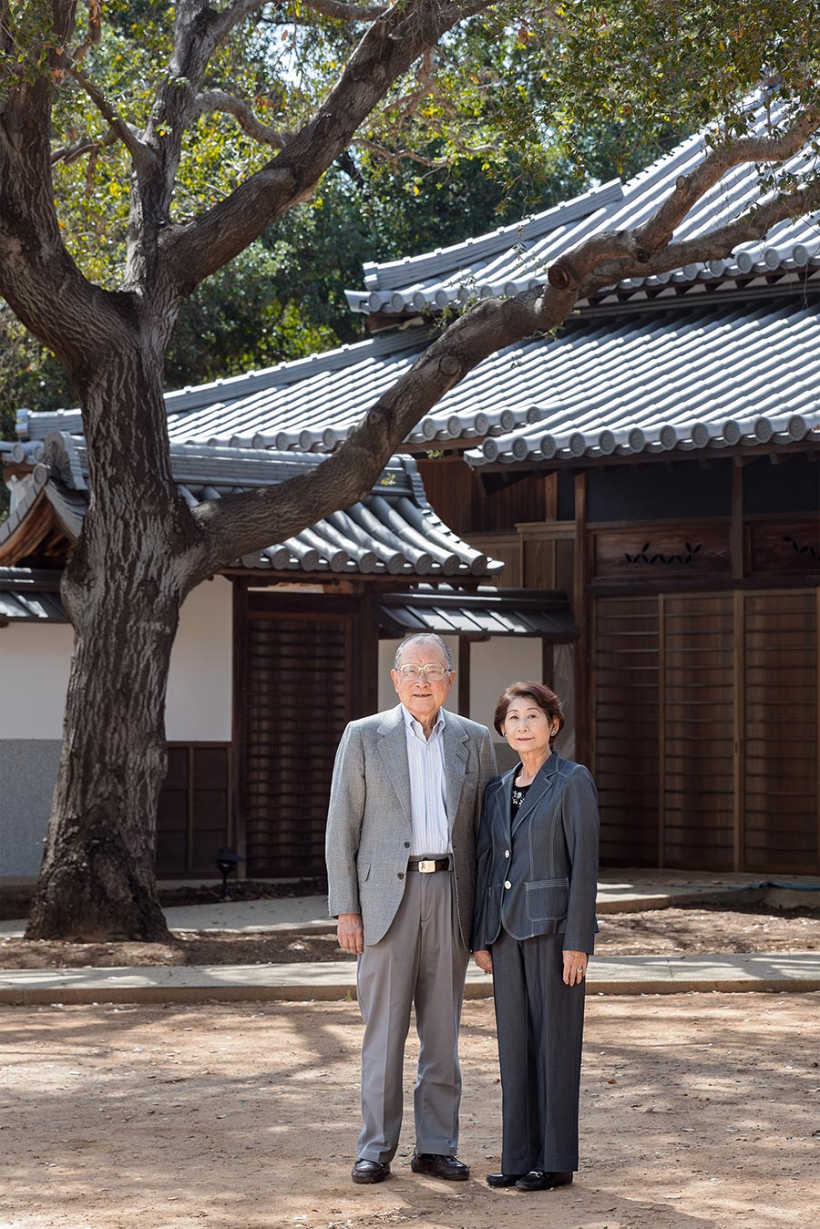 Two people stand in front of their restored ancestral home.