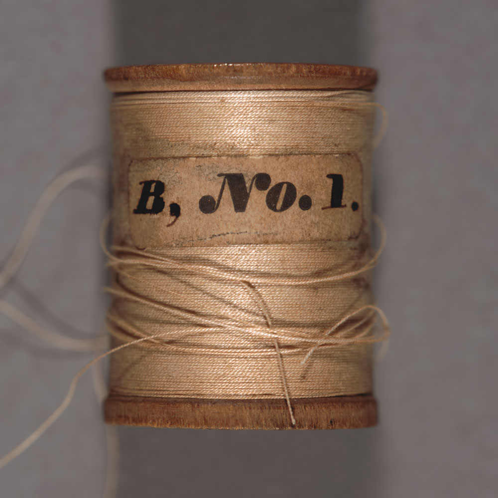 View of a spool of thread from the side. The text on the label reads “B, No. 1.”