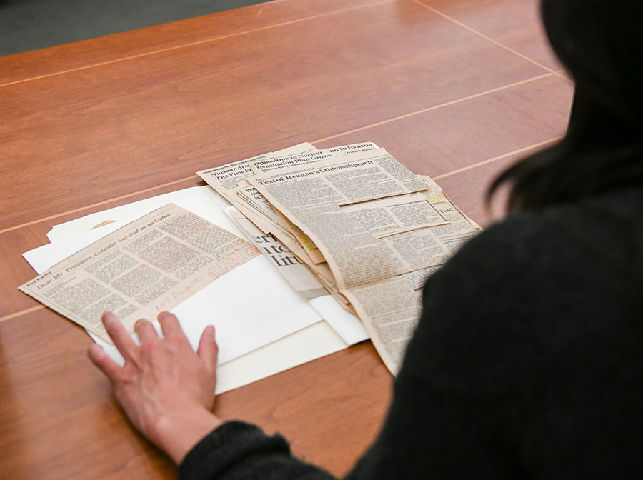 A person looks through a stack of newspaper clippings set a table.