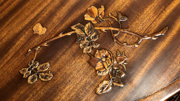 A wood table surface with inlaid floral design.