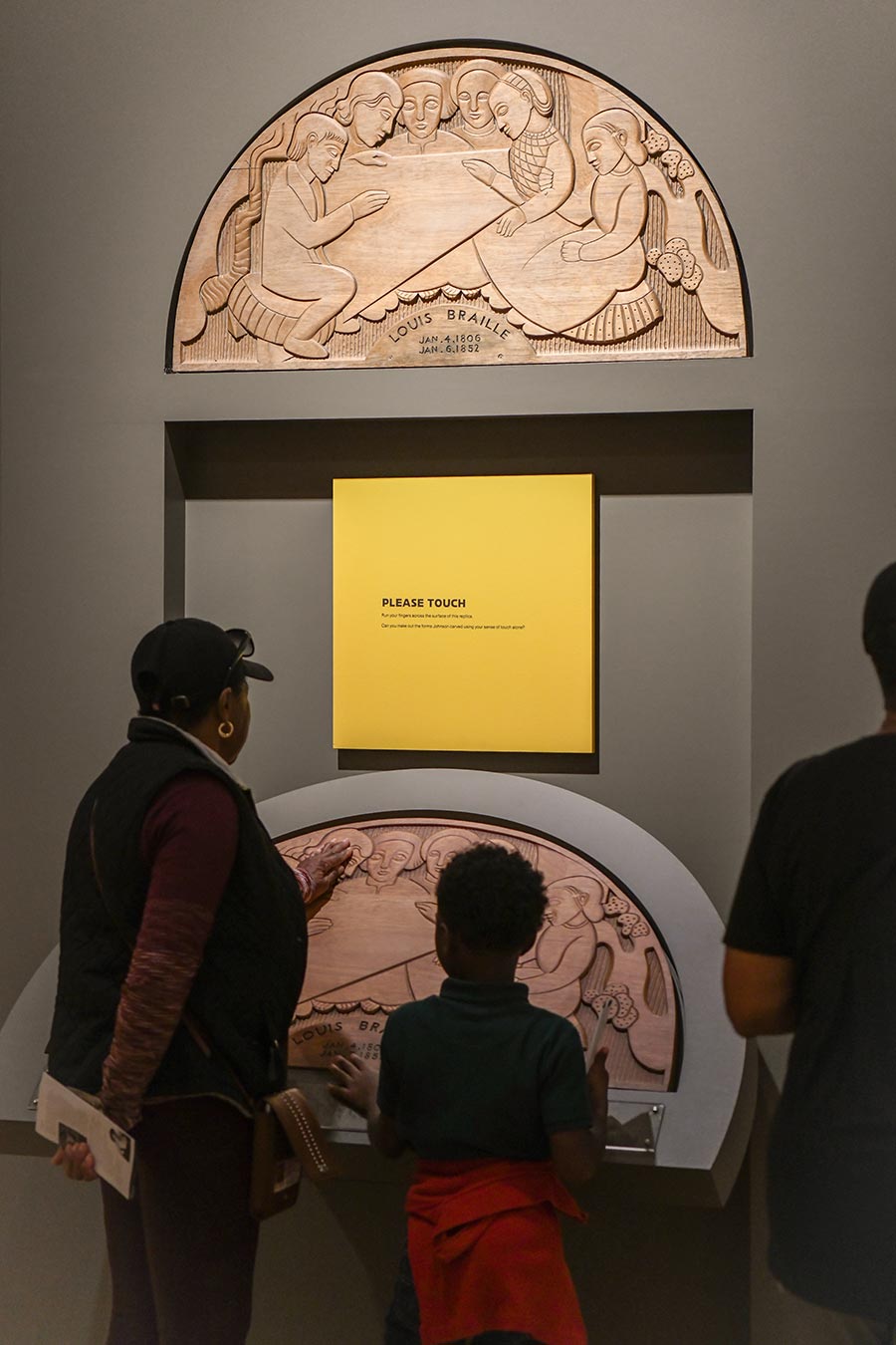 People look at and touch a replica of an art piece.