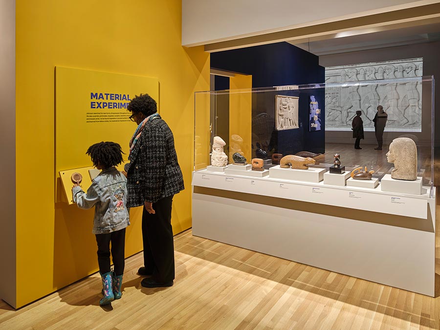 An adult and child look at items in an art gallery space.