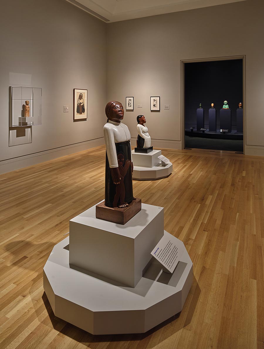 Interior view of a gallery room with art pieces on the walls and on pedestals.