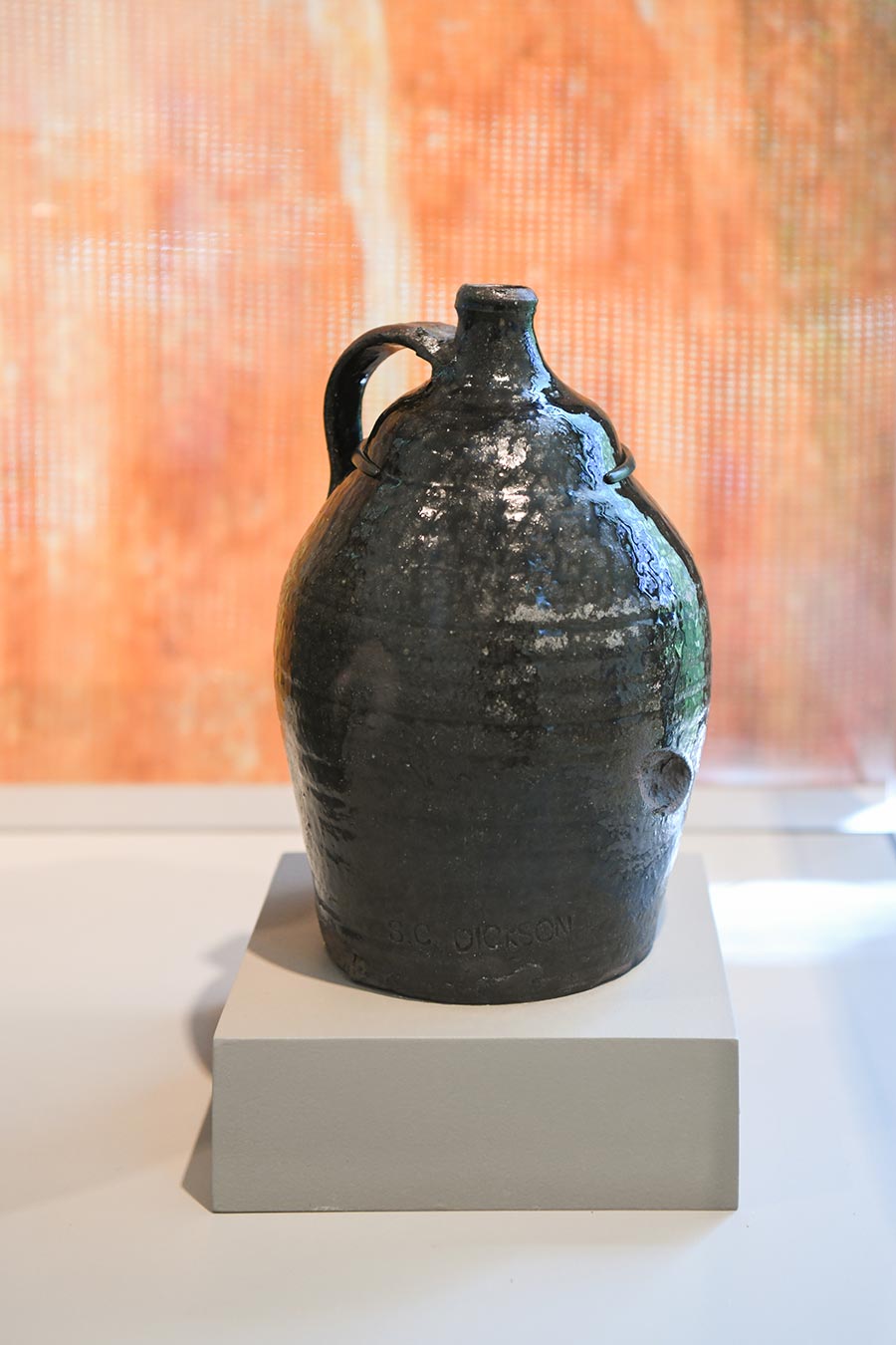 A glazed stoneware jug on a small riser.