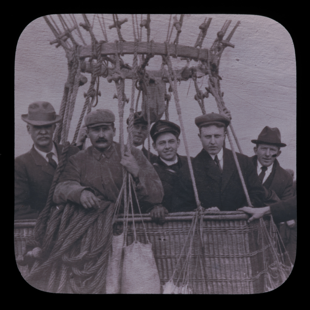 A group of people stand in the basket of a hot air balloon.