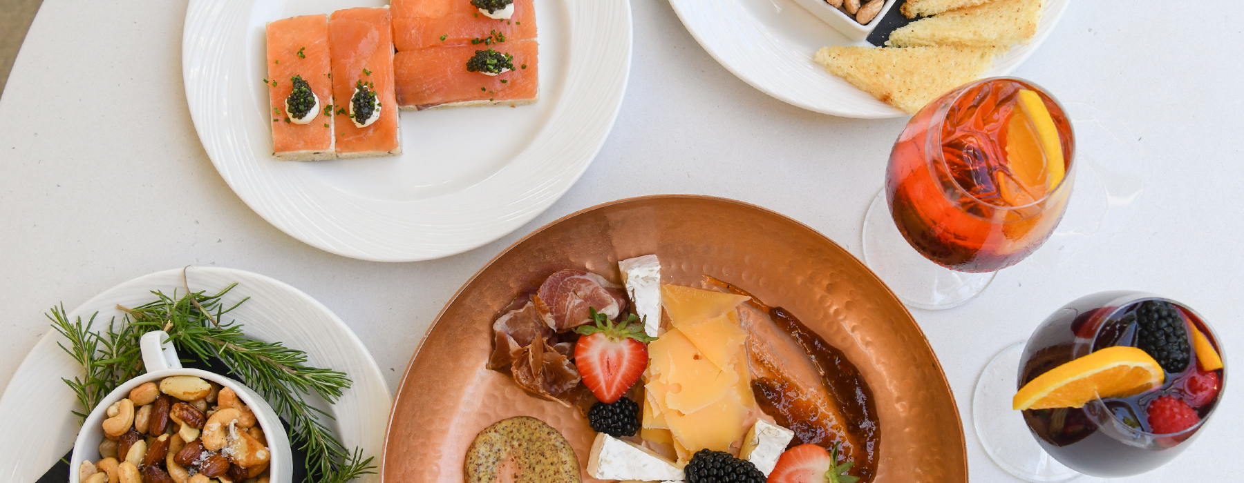 An overhead view of various plates and drinks on a white table.