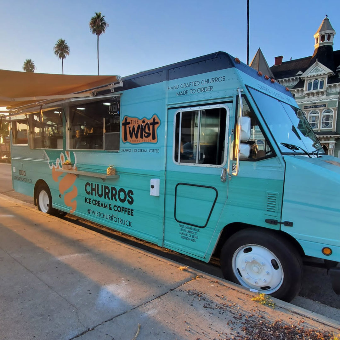 An aqua blue painted food truck sits parked at a curb.