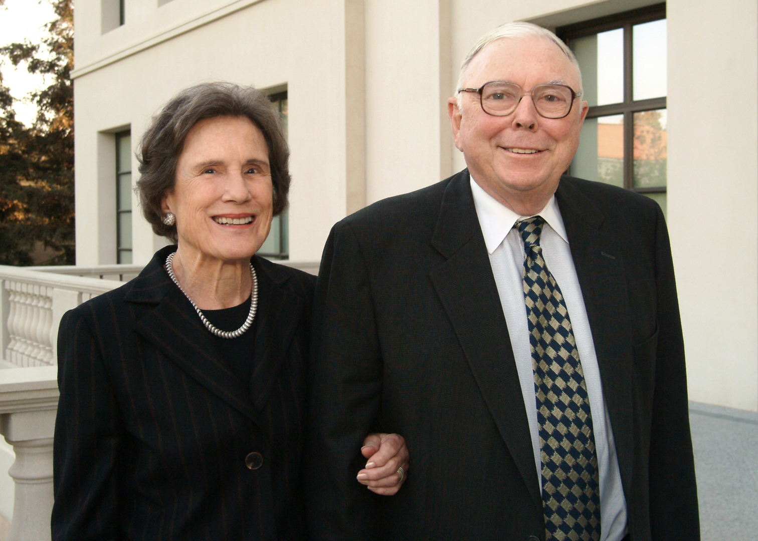 Two people in dark clothing smile at the camera.