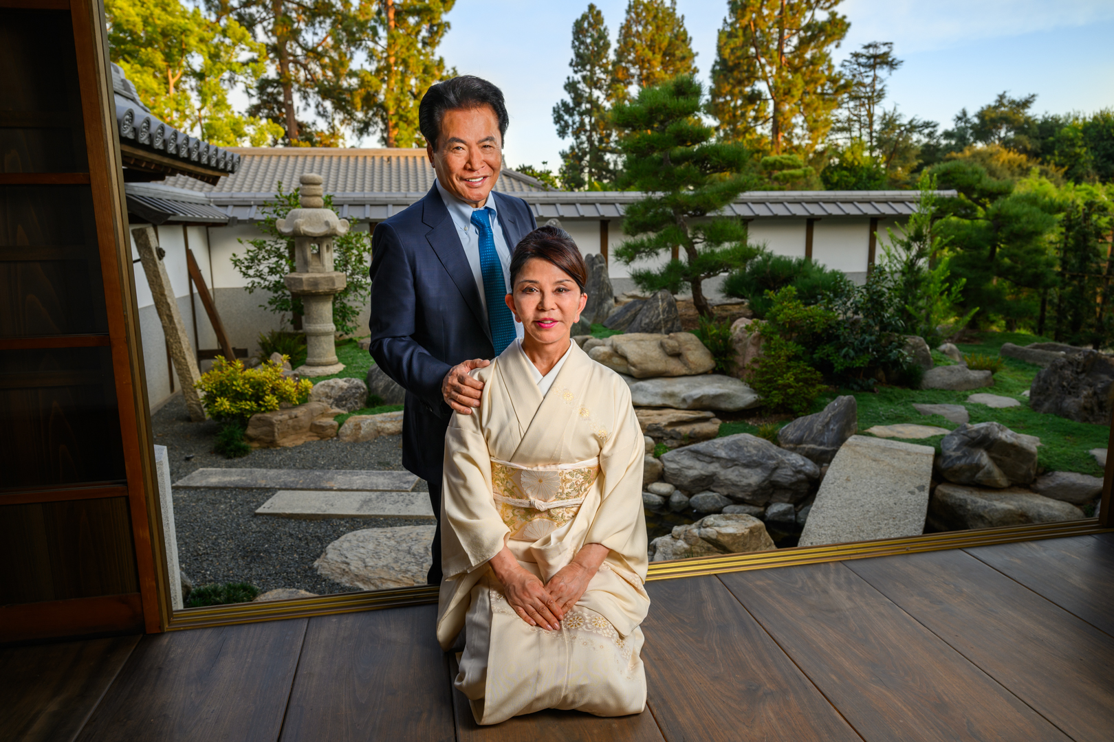 A couple pose in a traditional Japanese home with a large doorway that opens into a garden.