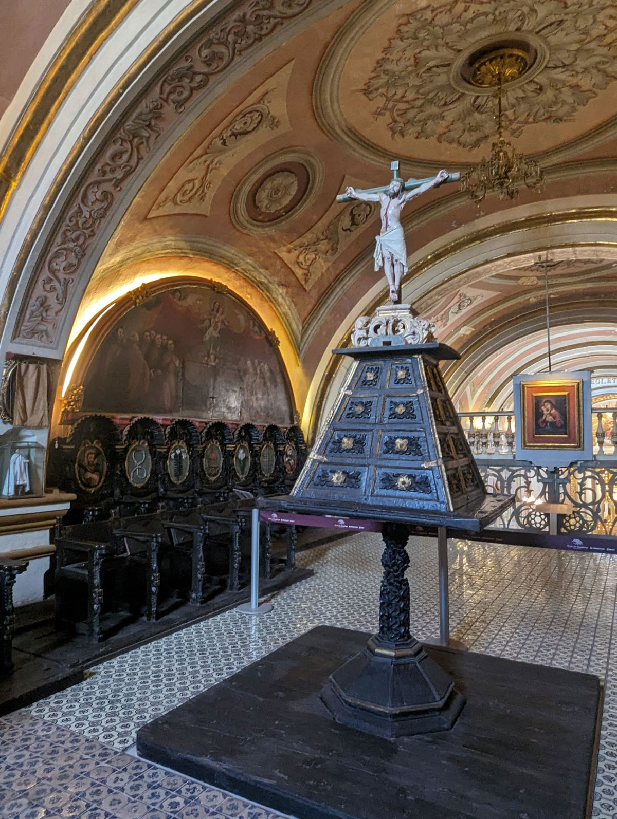 Historic church choir loft with ornate crucifix stand and decorative ceiling.