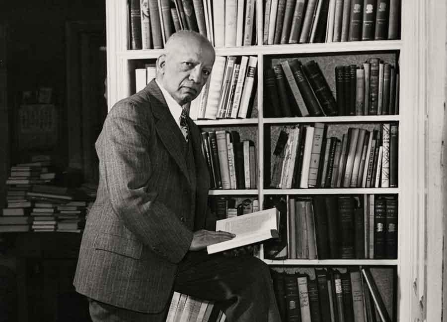 Carter G. Woodson posed in front of a bookshelf