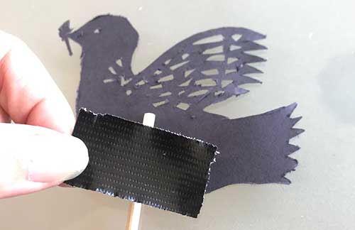 Taping a bamboo stick to dove shadow puppet