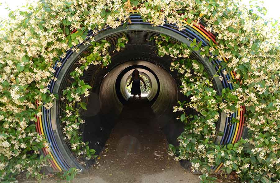 A child explores a rainbow tunnel filled with prism-scattered light in the Helen and Peter Bing Children’s Garden. The Huntington Library, Art Museum, and Botanical Gardens.