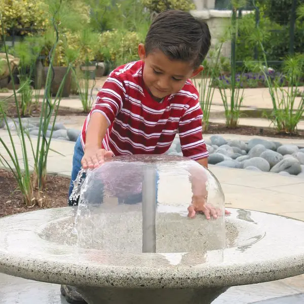 young boy playing in water feature