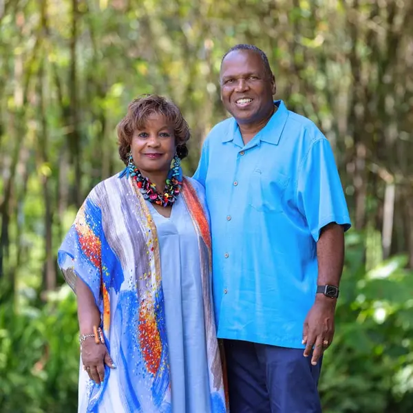 A couple dressed in blue stands among a grove of bamboo and ferns.