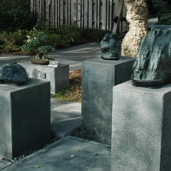 Decorative "viewing stones" sit atop concrete pedestals in a garden.