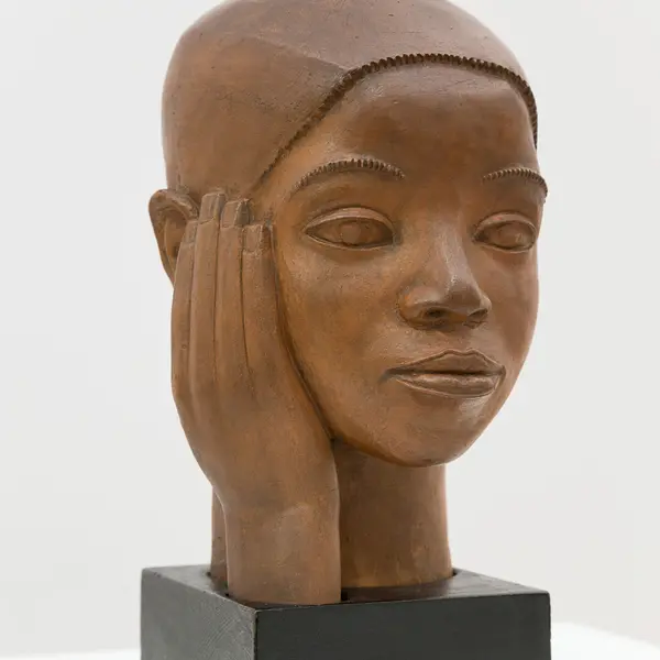 sculpture of wooden head with hand on side of face