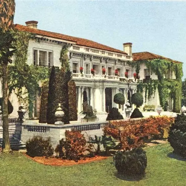 A color photo of a 1920s mansion with a manicured lawn.